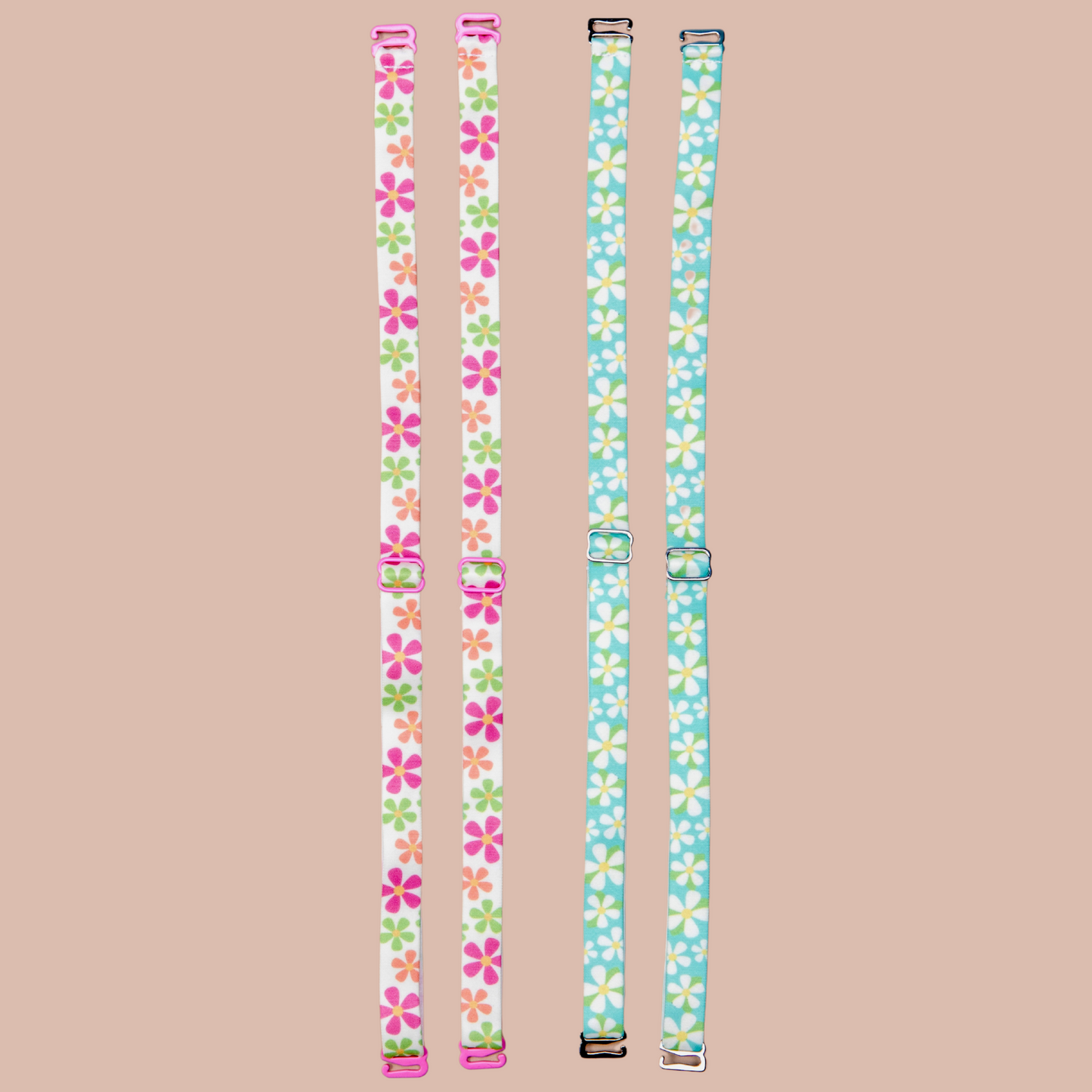 Left - May Flowers Her-Rah bra Straps - white straps with a mix of daisy like flowers in green, orange and pink with yellow center, featuring pink coated hardware. Dunk'n Daisies Her-Rah bra straps - Blue straps with white daisy like flowers with yellow center and green leaves, featuring silver hardware.