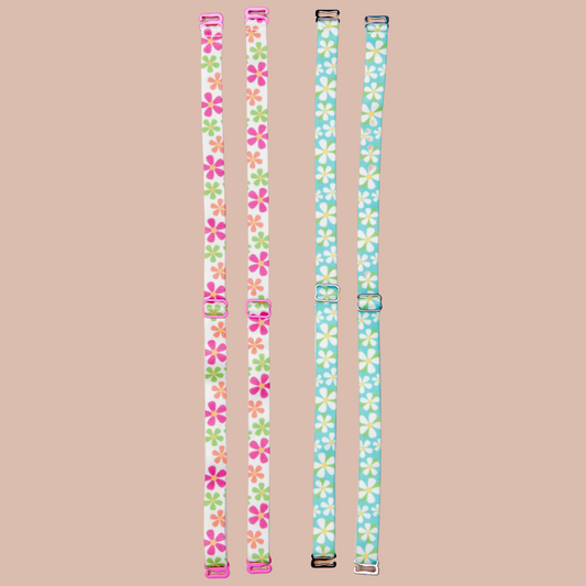Left - May Flowers Her-Rah bra Straps - white straps with a mix of daisy like flowers in green, orange and pink with yellow center, featuring pink coated hardware. Dunk'n Daisies Her-Rah bra straps - Blue straps with white daisy like flowers with yellow center and green leaves, featuring silver hardware.