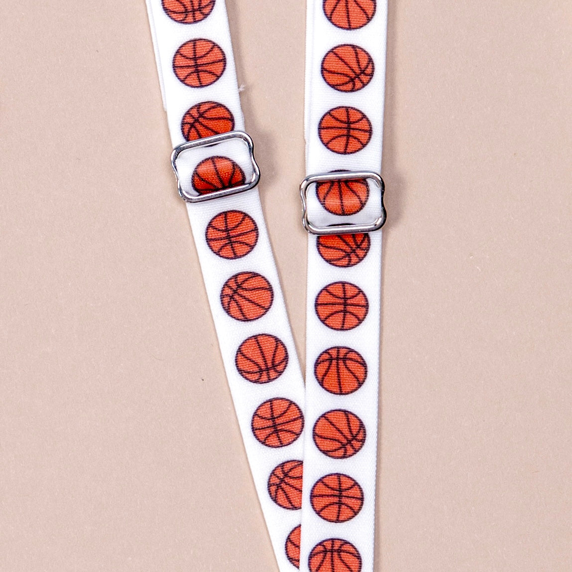 white straps with orange basketballs repeating along length of material, featuring silver metal hardware.