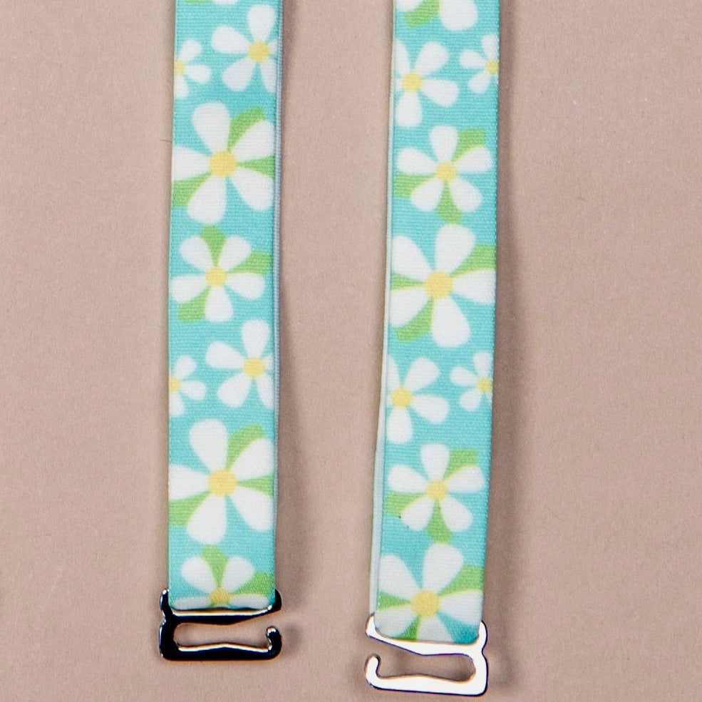 Dunk'n Daisies Her-Rah bra straps - Blue straps with white daisy like flowers with yellow center and green leaves, featuring silver hardware.