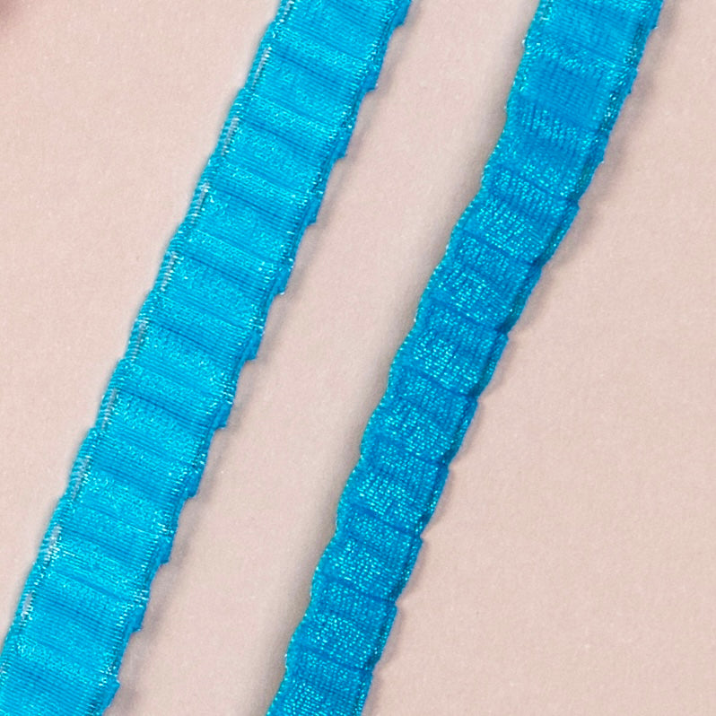 Close up on a set of interchangeable her-rah bra straps in a pleated organza patterns with a sheer shimmer to the fabric in color Blue Blast.