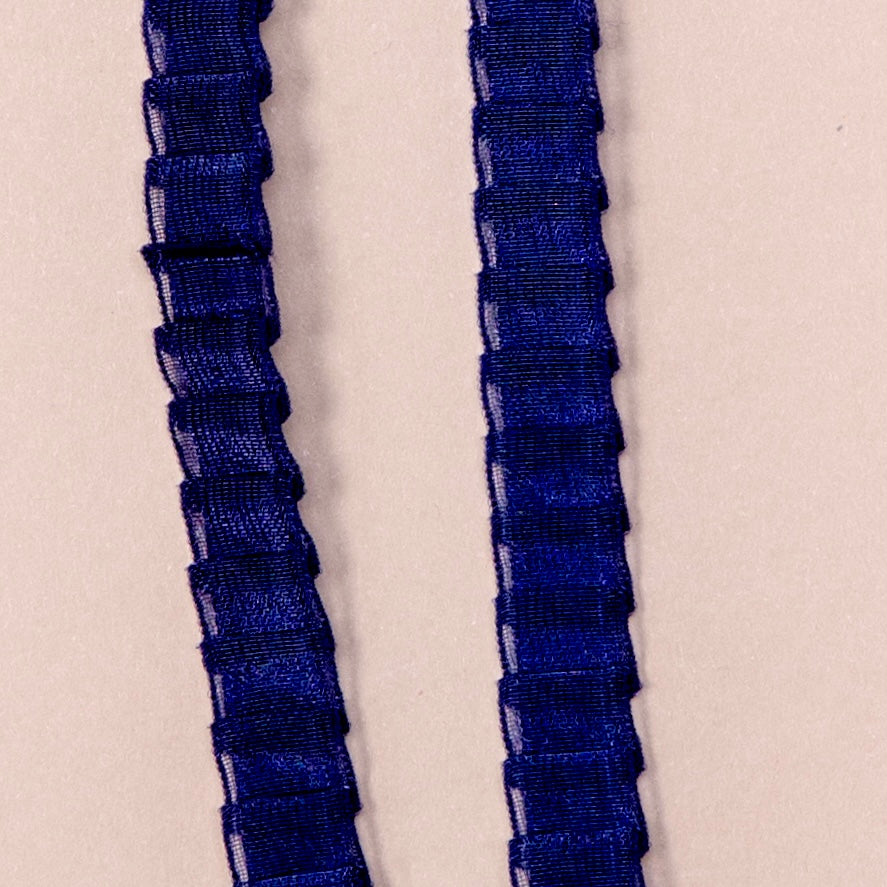 Close up on a set of interchangeable her-rah bra straps in a pleated organza patterns with a sheer shimmer to the fabric in color Navy Blue.
