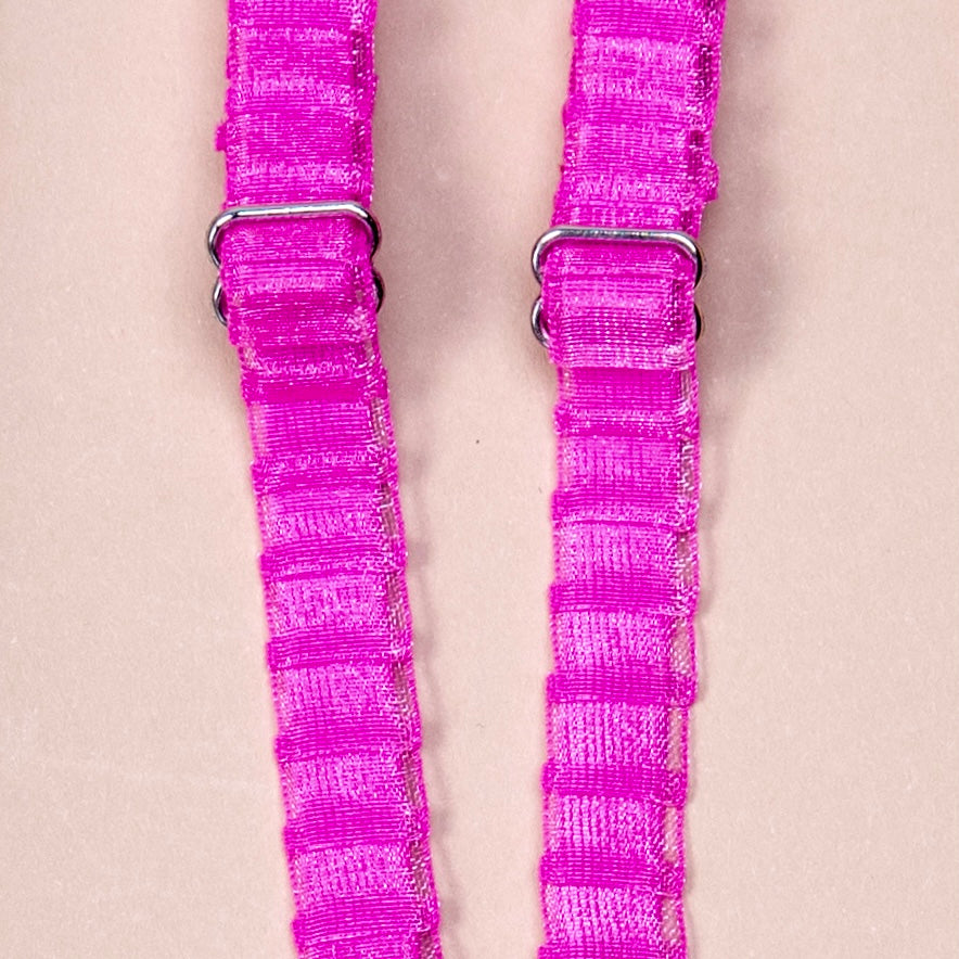 Close up on a set of interchangeable her-rah bra straps in a pleated organza patterns with a sheer shimmer to the fabric in color Hot Pink.