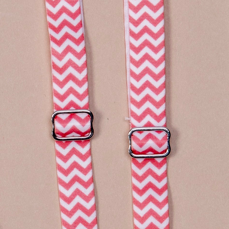 Close up on a set of interchangeable her-rah bra straps in chevron patterns with alternating stripes of apricot (or pinkish orange) and white.
