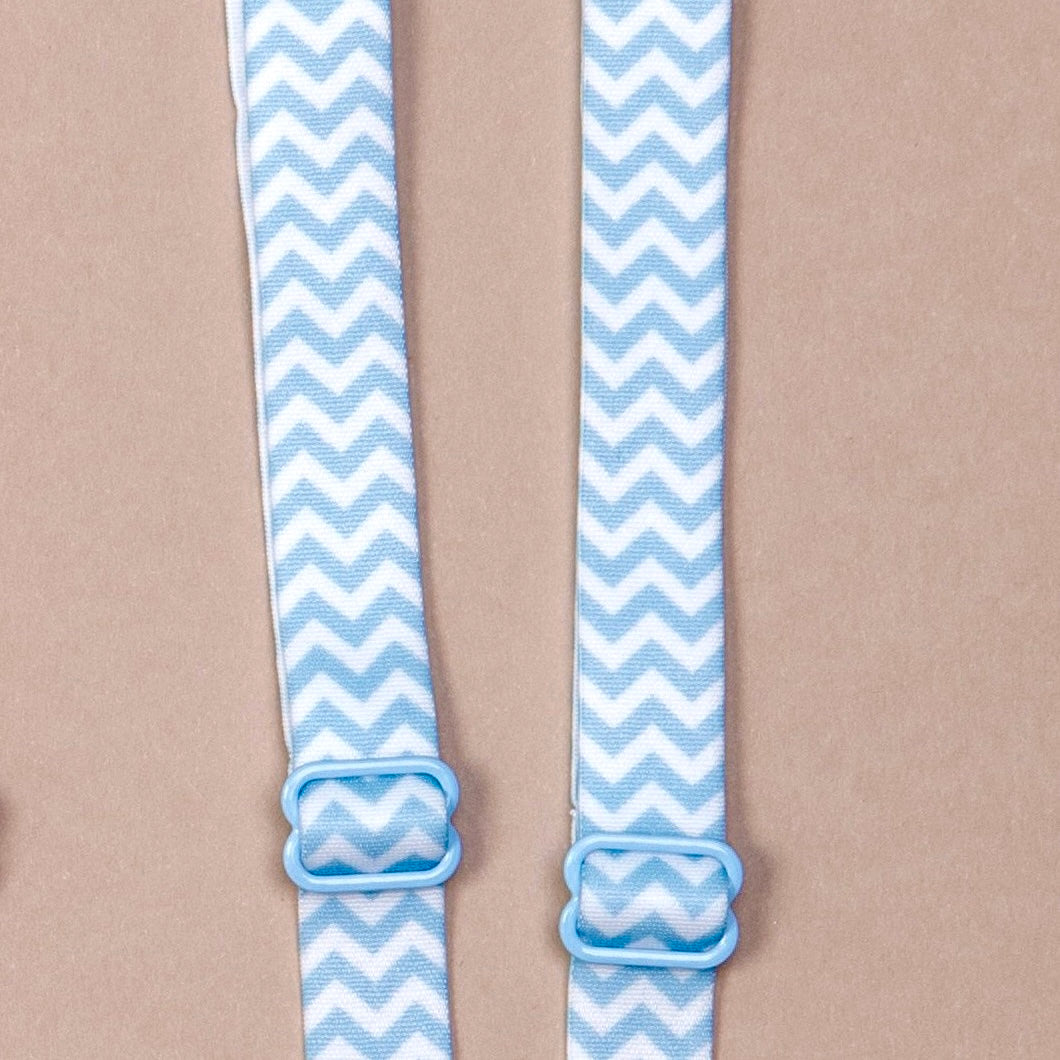 Close up on a set of interchangeable her-rah bra straps in chevron patterns with alternating stripes of baby blue and white.