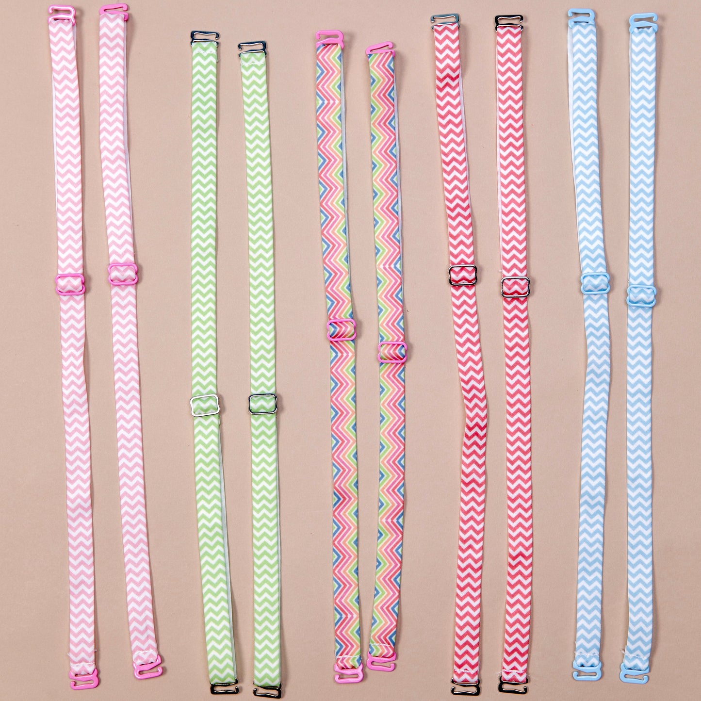 5 sets of interchangeable her-rah bra straps in chevron patterns of various colors, from left to right: flamingo Pink and white, apple green and white, rainbow, apricot and white, baby blue and white.