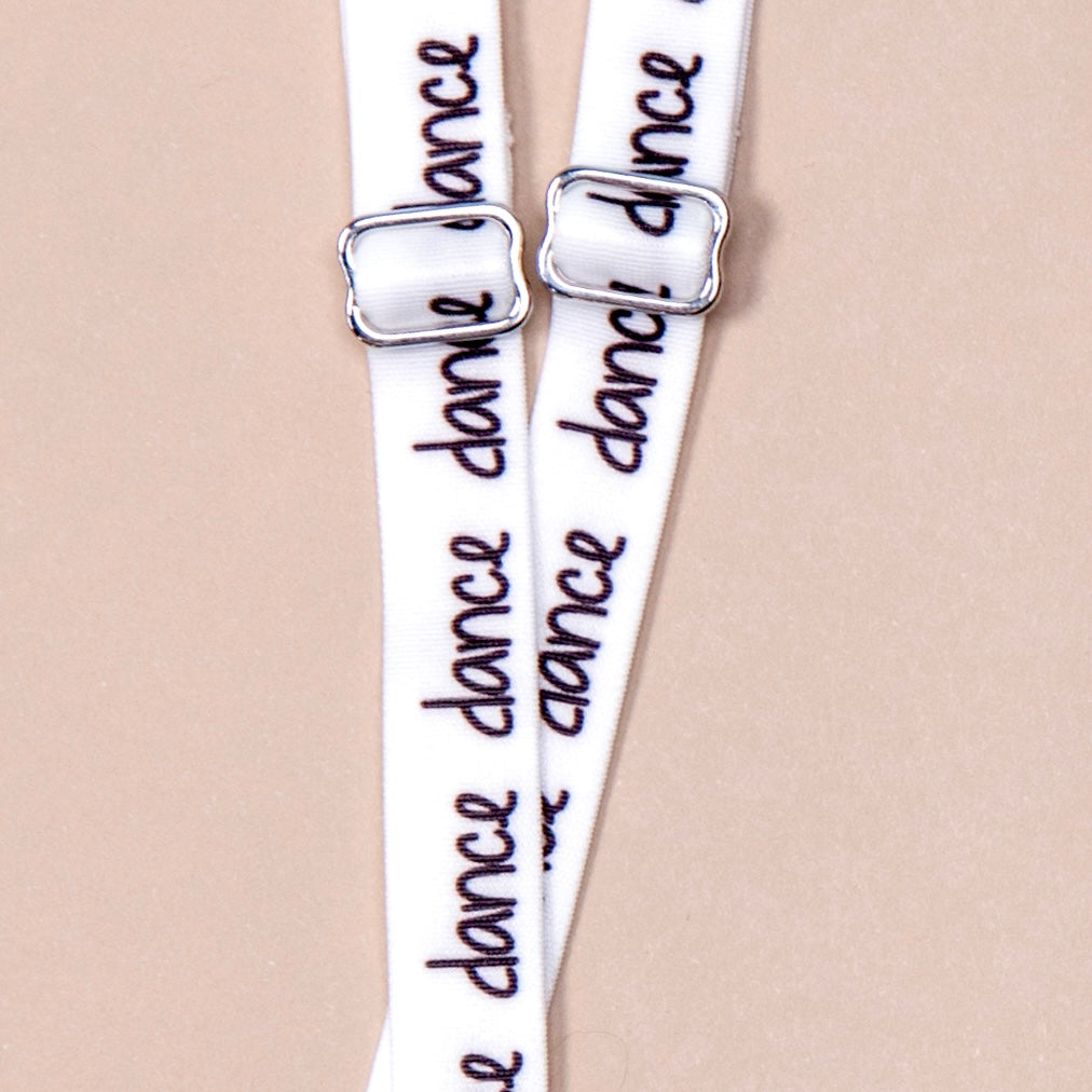 White straps with the word dance in black handwritten font repeating along length of material, featuring silver metal hardware.