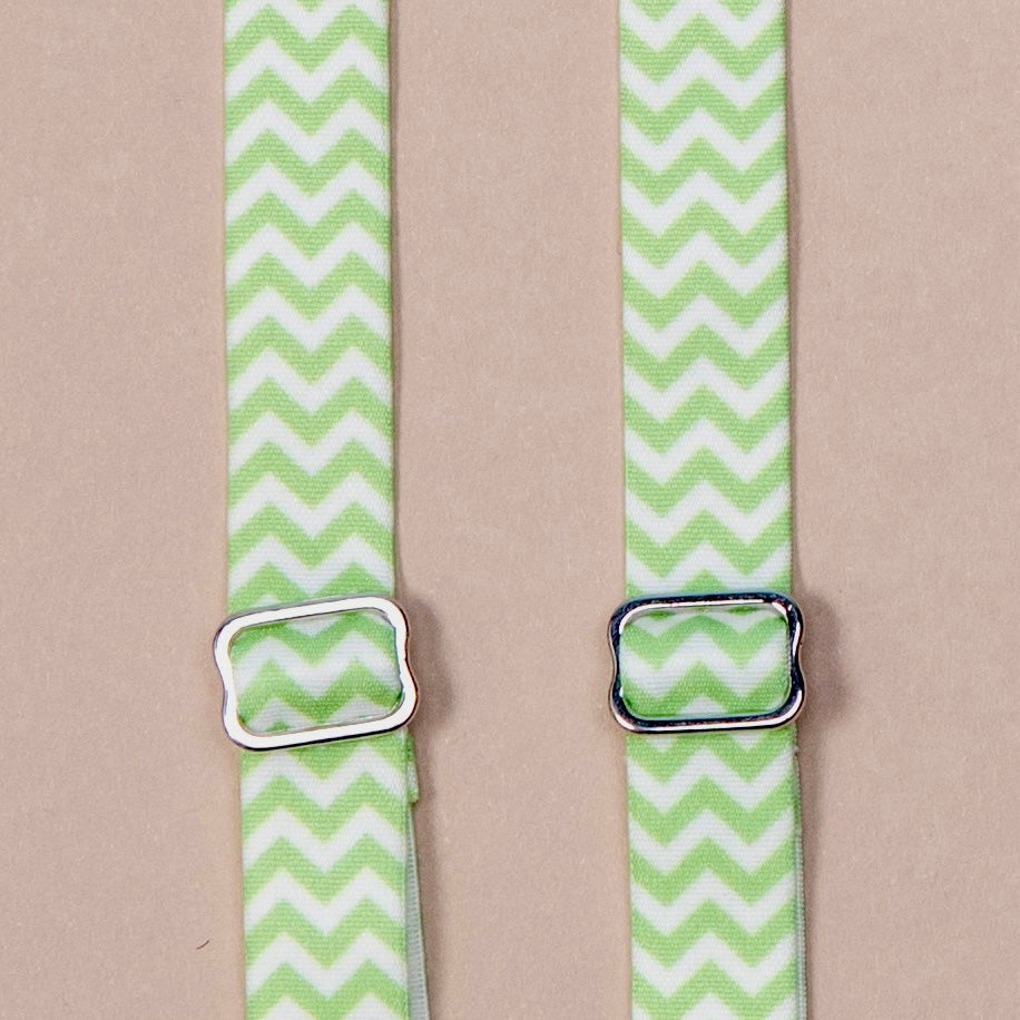 Close up on a set of interchangeable her-rah bra straps in chevron patterns with alternating stripes of Apple Green and white.